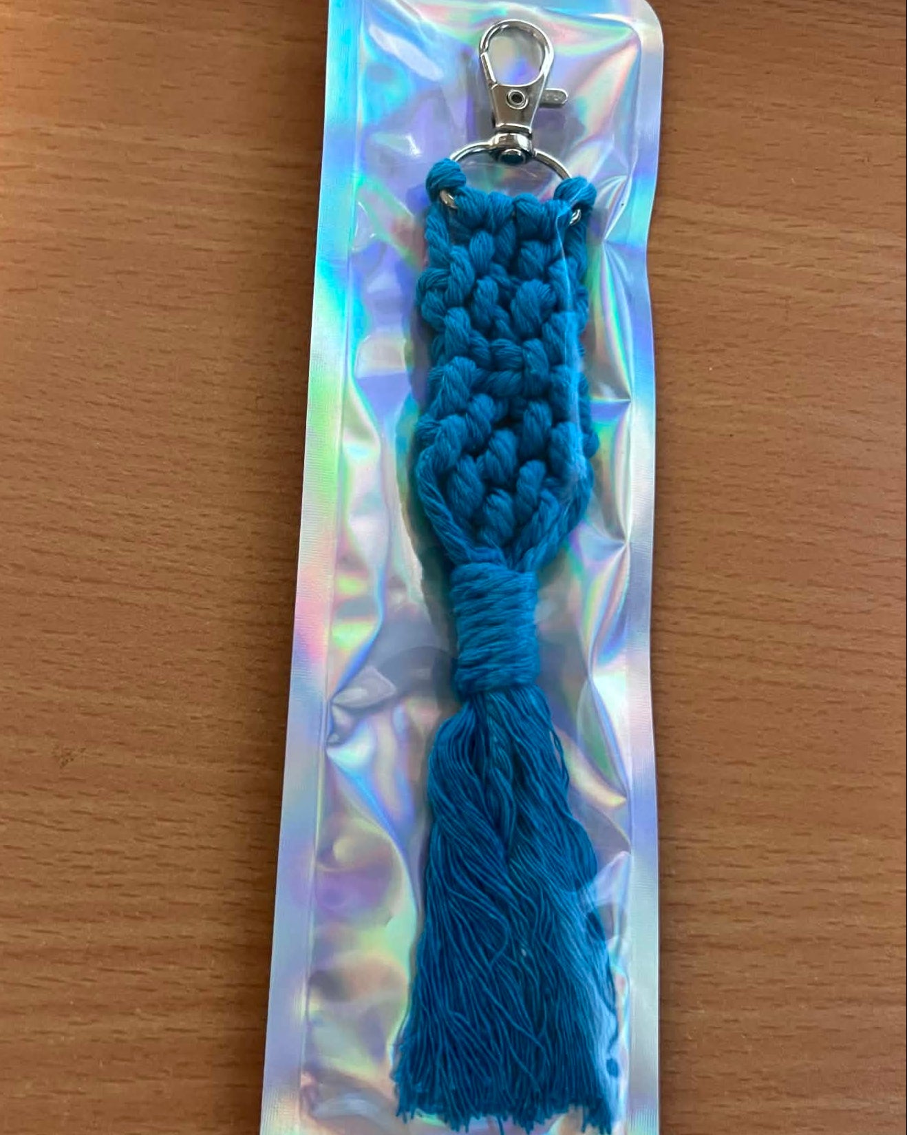 Blue braided keychain on a reflective card with a wooden surface background