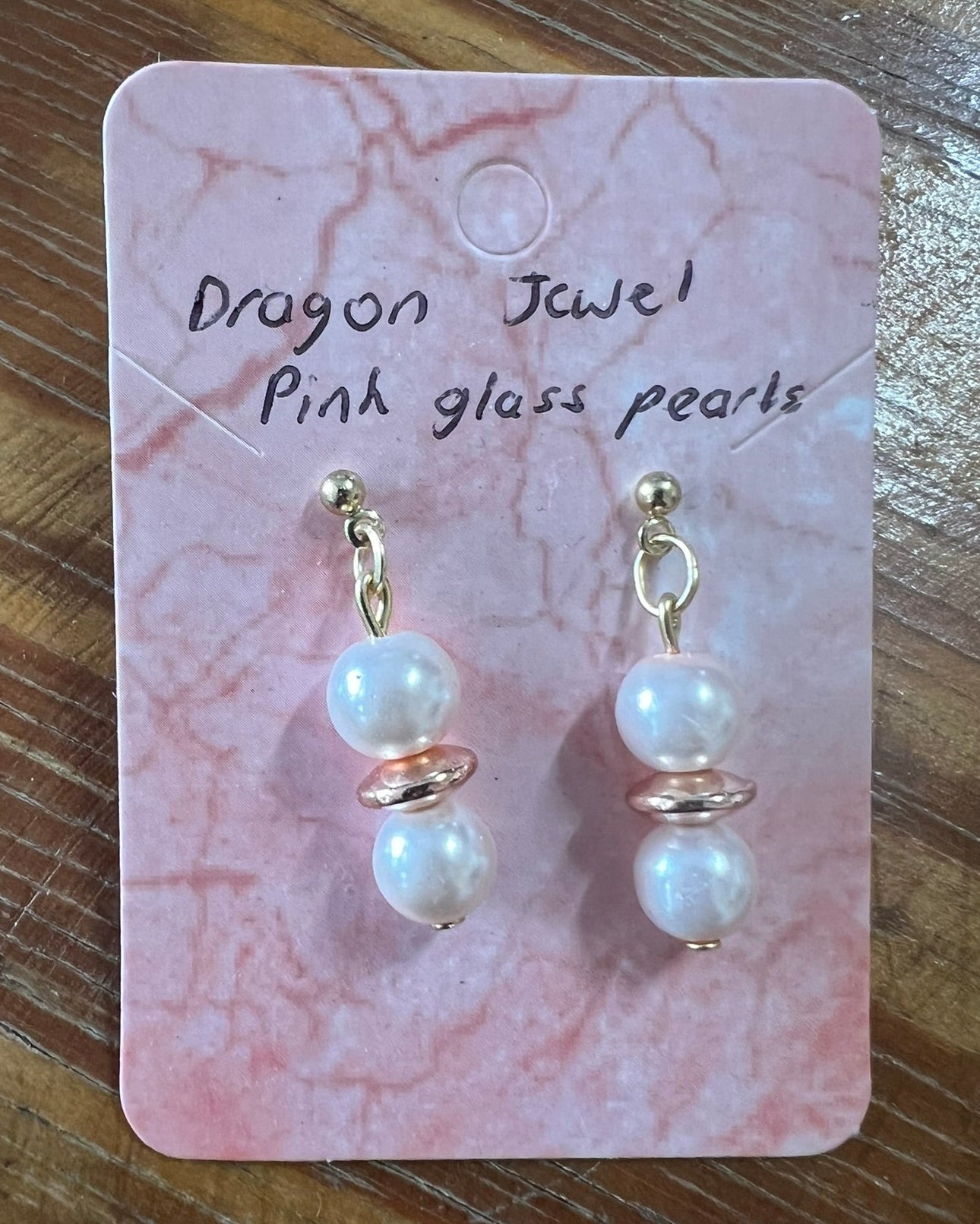 Pair of pearl earrings on a pink marbled card with 'Dragon Jewel' text.