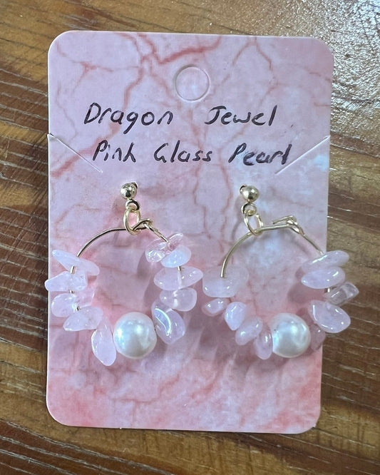 Pair of earrings on a pink marble card with 'Dragon Jewel Pink Glass Pearl' text, placed on a wooden surface.
