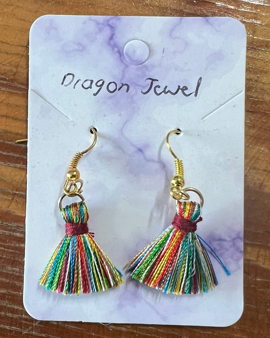 Colorful tassel earrings on a 'Dragon Jewel' branded card, placed on a wooden surface.