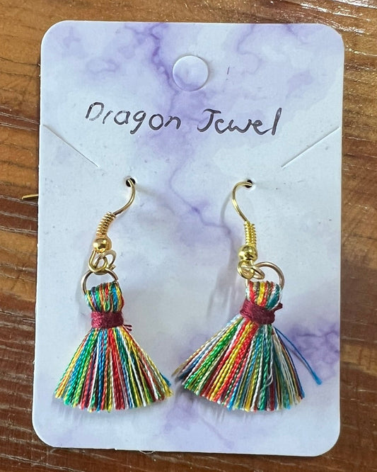 Colorful tassel earrings on a 'Dragon Jewel' branded card, placed on a wooden surface.
