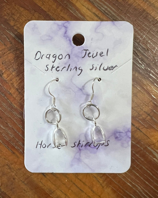 Silver earrings on a 'Dragon Jewel' branded card against a wooden background