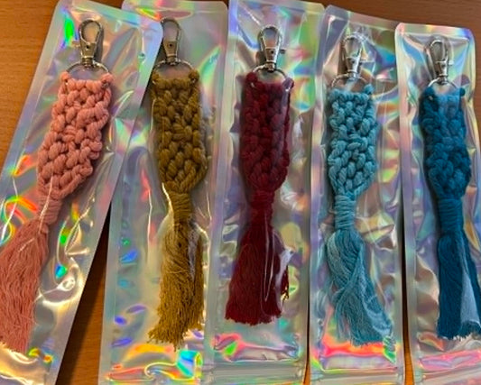 Set of colorful macrame keyrings tassels in clear packaging on a wooden surface