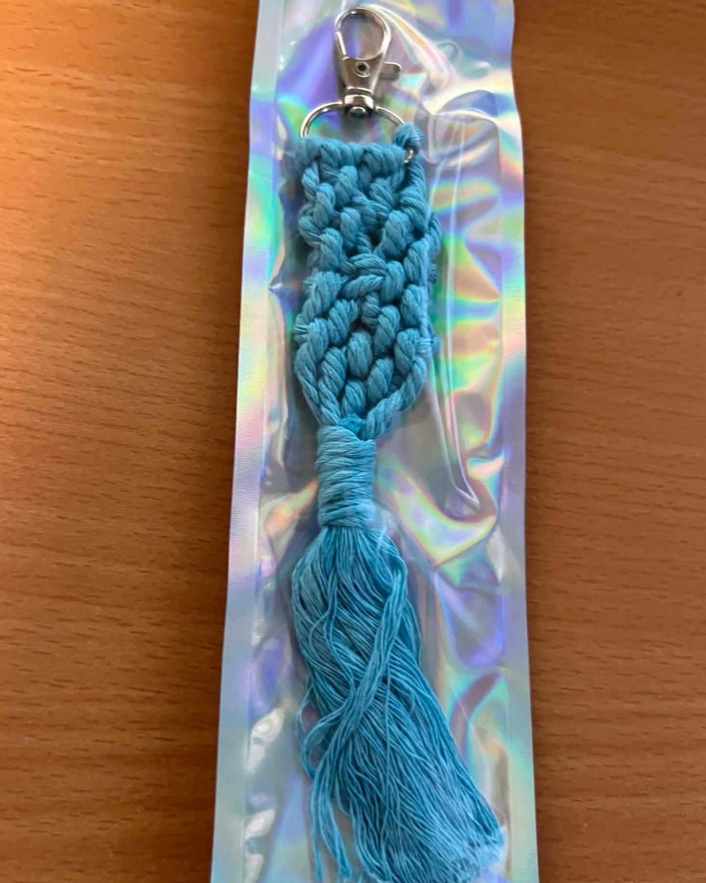 Blue braided keychain on a reflective card with a wooden surface background