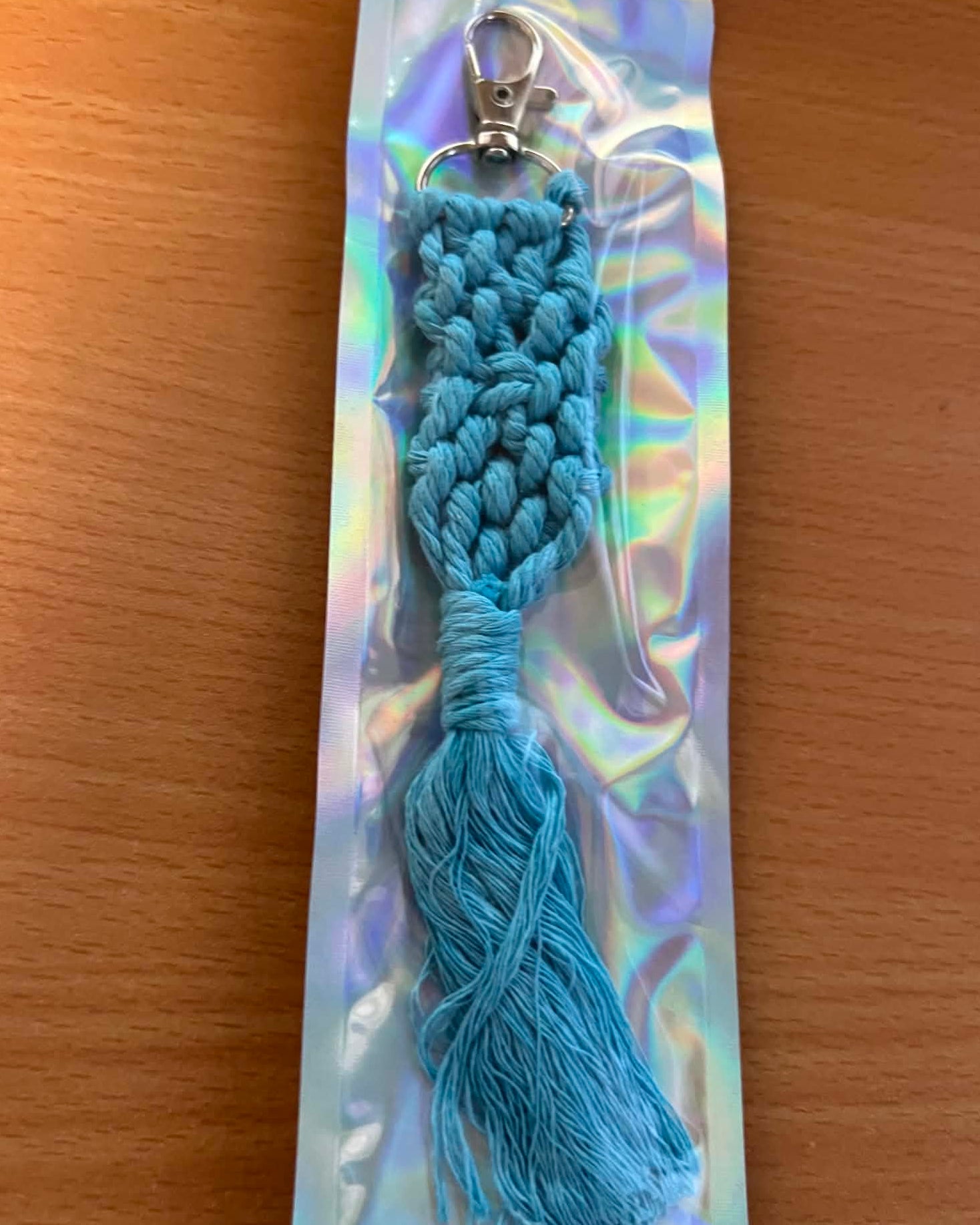 Blue braided keychain on a reflective card with a wooden surface background