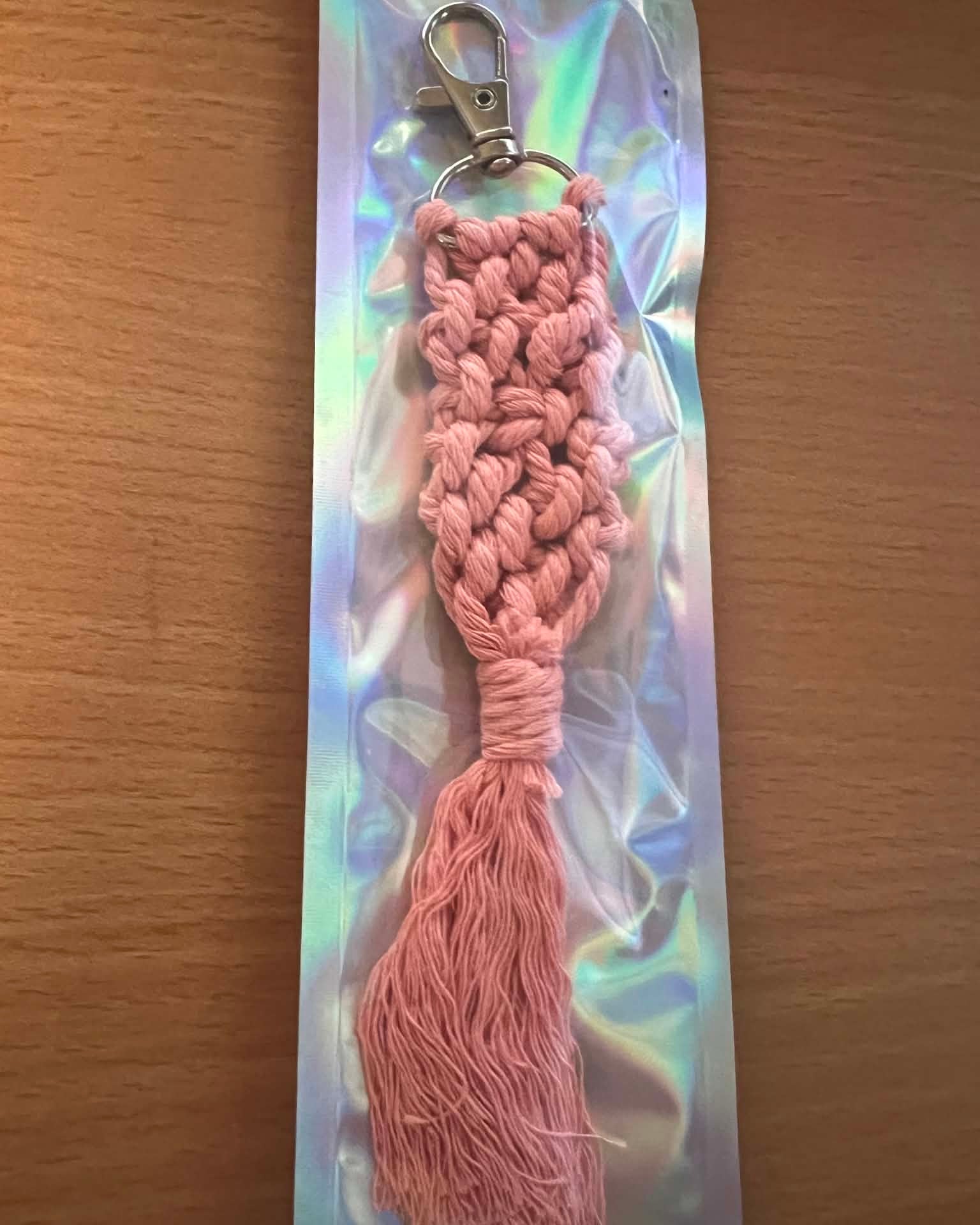 Peach braided keychain with tassel on a reflective card against a wooden background