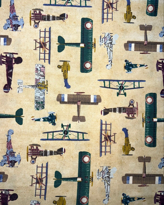 Vintage-style fabric pattern featuring multiple illustrated biplanes and a few small figures on a warm beige background.